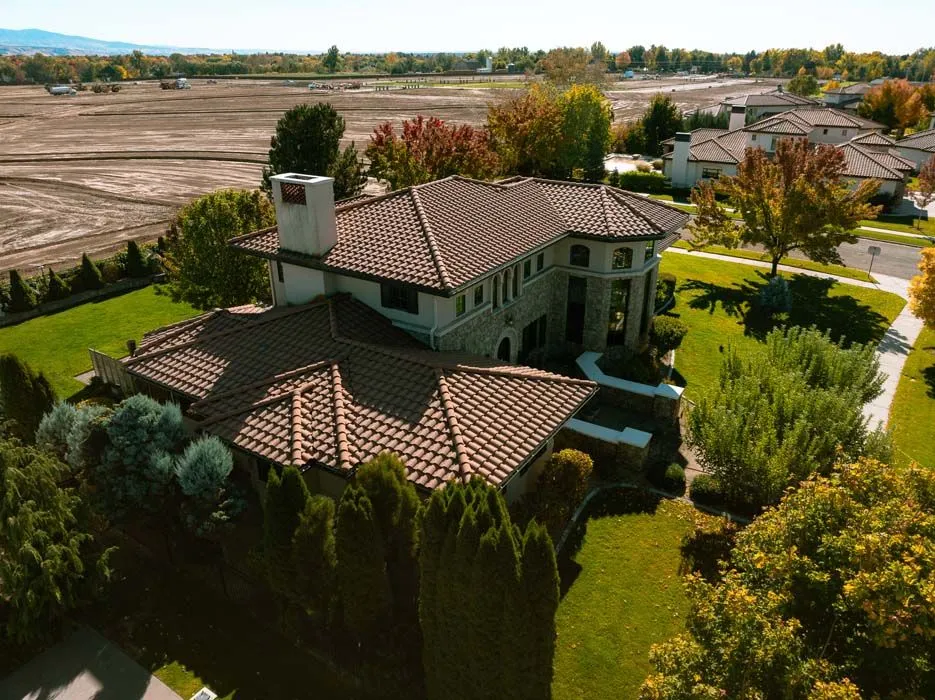 Luxury home with a terracotta tile roof, surrounded by green lawns and trees.