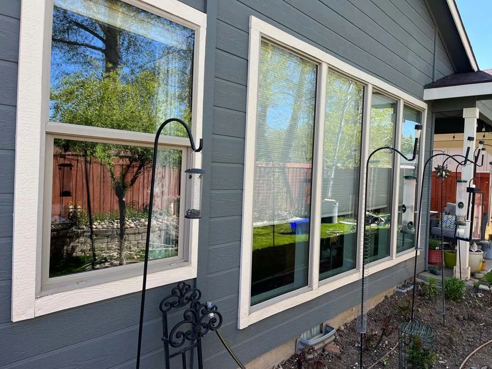 Exterior view of gray house with several windows, white trim, and a small garden.