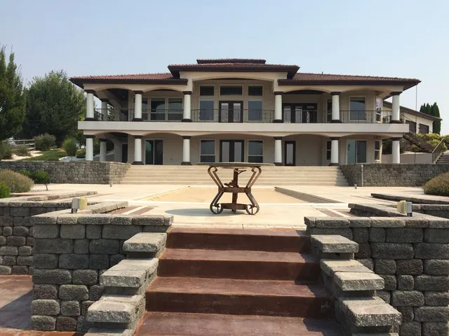 Large house with a red tile roof and multiple columns. Exterior steps lead to the front entrance.