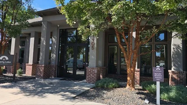 Exterior of a building with glass doors, brick accents, and a sign that says 