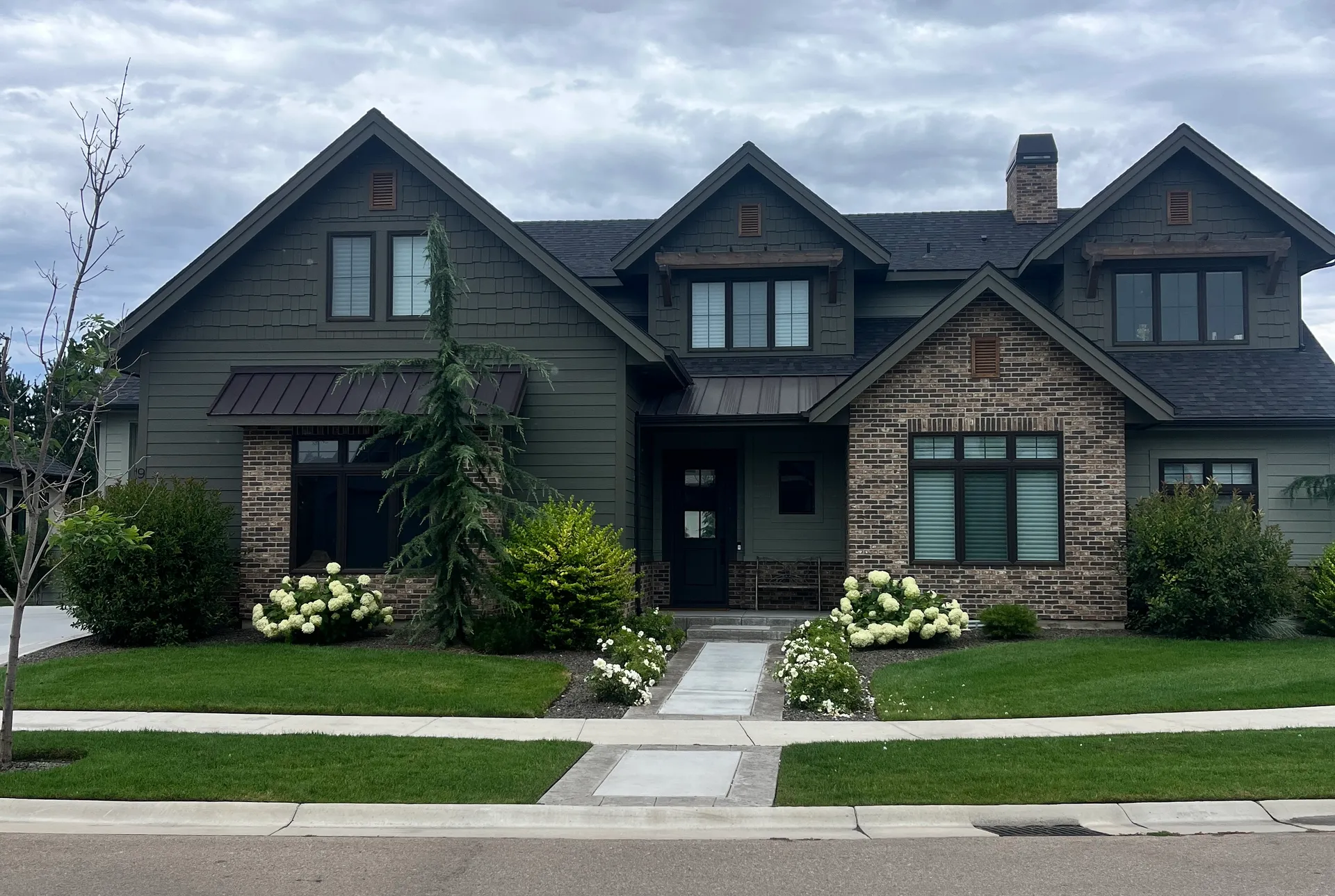 Green craftsman home in Boise with clean, streak-free windows and manicured landscaping viewed from the street Green craftsman home in Boise with clean, streak-free windows and manicured landscaping viewed from the street