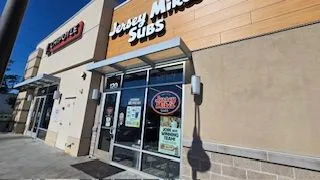 Exterior of a Jersey Mike's Subs restaurant storefront with large glass windows and an awning.