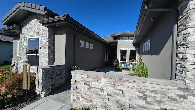 Modern house exterior with stone and stucco facade on a sunny day.