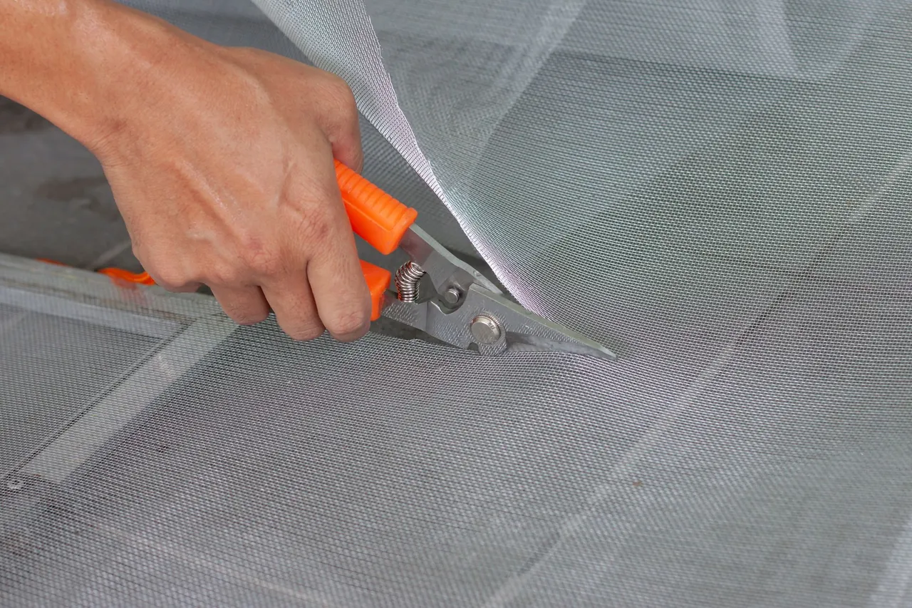 Technician cutting new mesh during a mobile window screen repair in Boise, ID